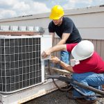 Two men working on an air conditioning unit.